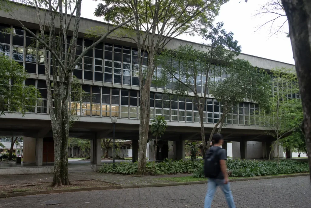nota de corte da ufmg no Sisu: prédio acadêmico de universidade federal com estudante revisando material sobre a mesa