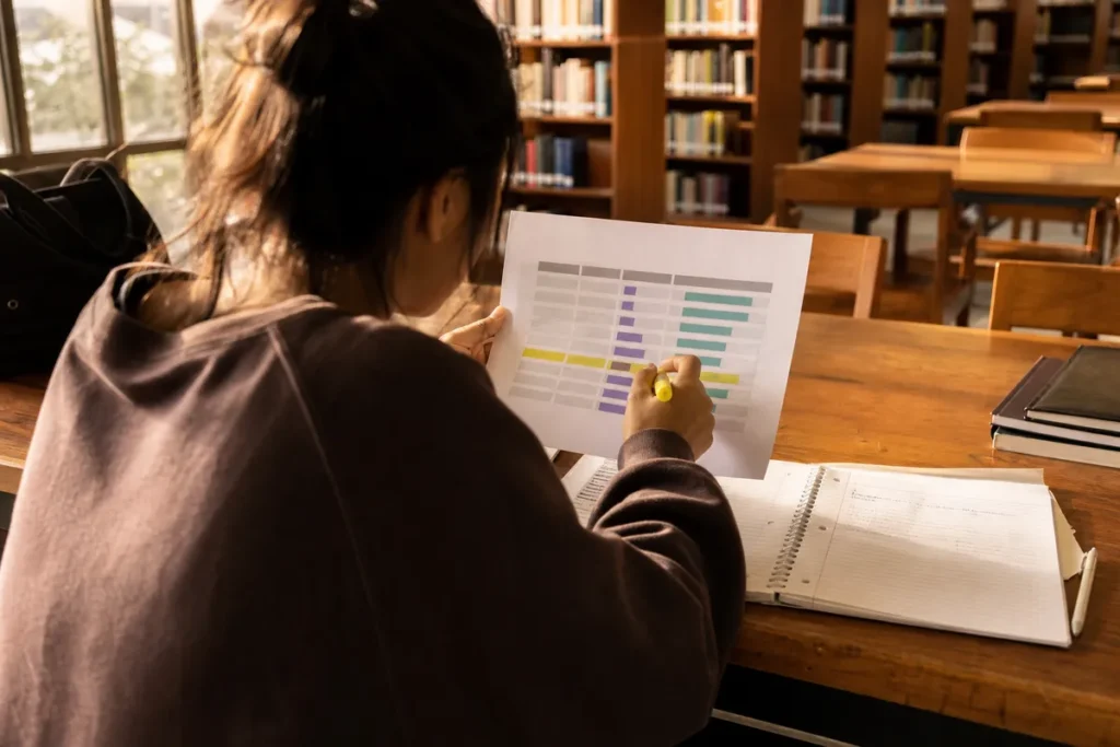 nota de corte da ufmg: estudante comparando notas de corte de diferentes cursos numa tabela impressa