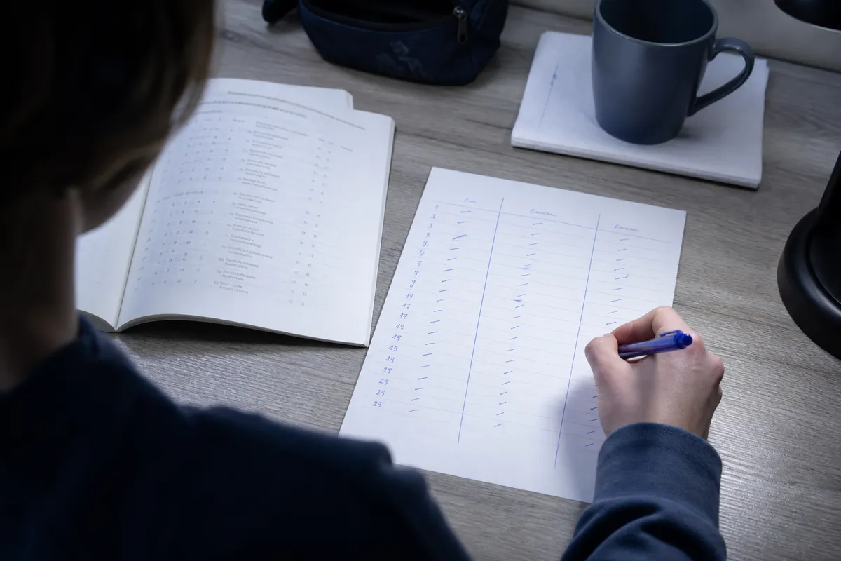 Prova do Enem 2024: estudante preenchendo a tabela de diagnóstico por assunto ao lado do caderno de prova aberto